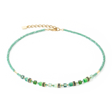 A gold necklace with bright green beads and stones