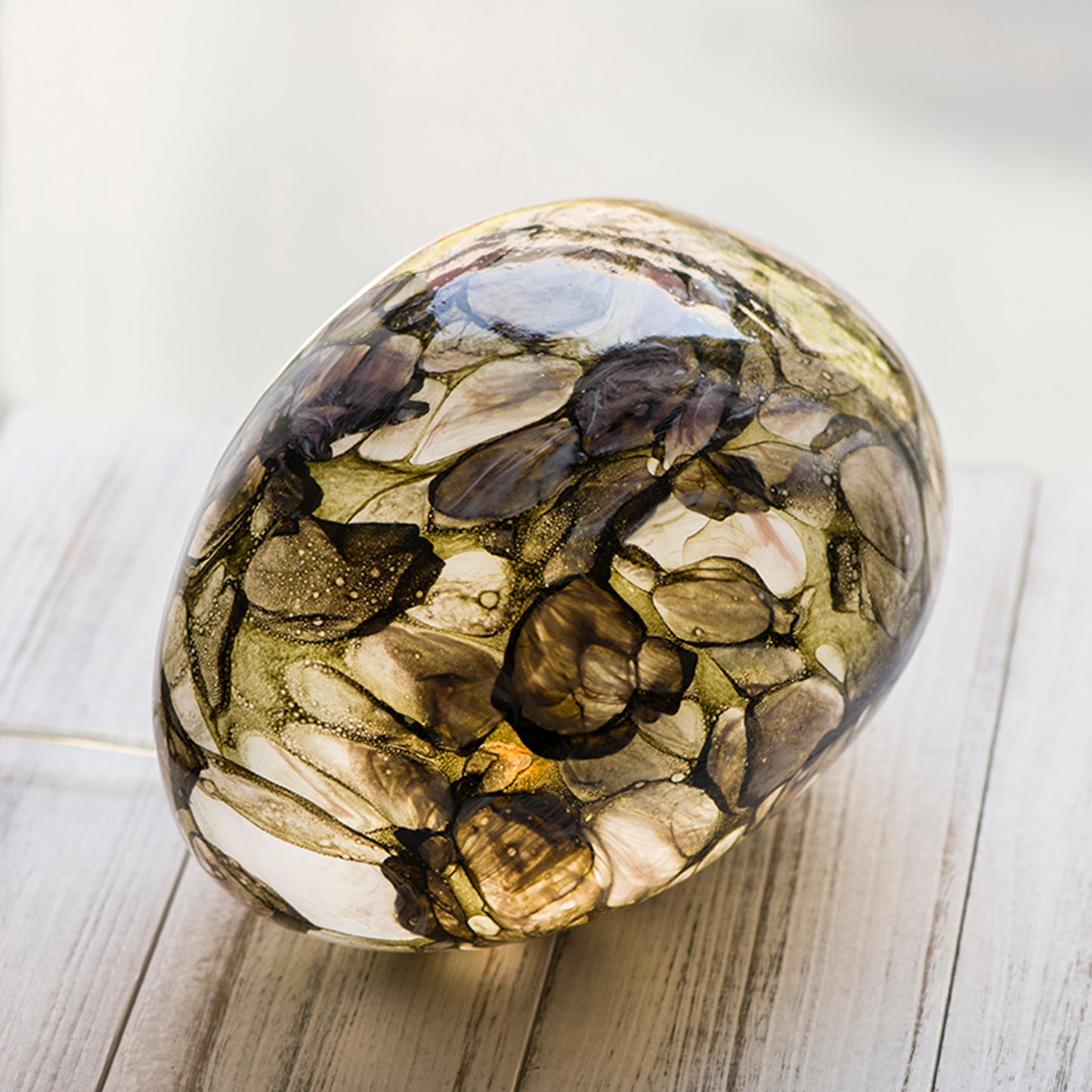 A pebble shaped glass lamp with a design based on sun dappled rivers top view