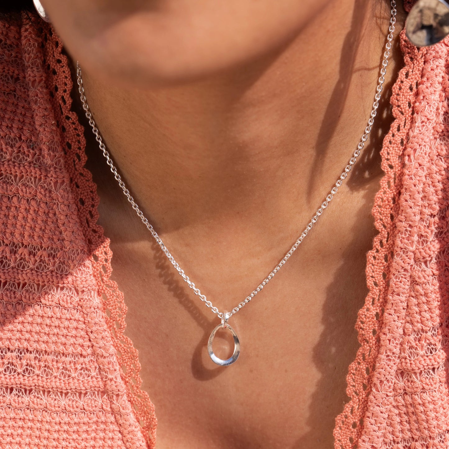 Model wearing necklace with three linked organic oval shapes in sterling silver