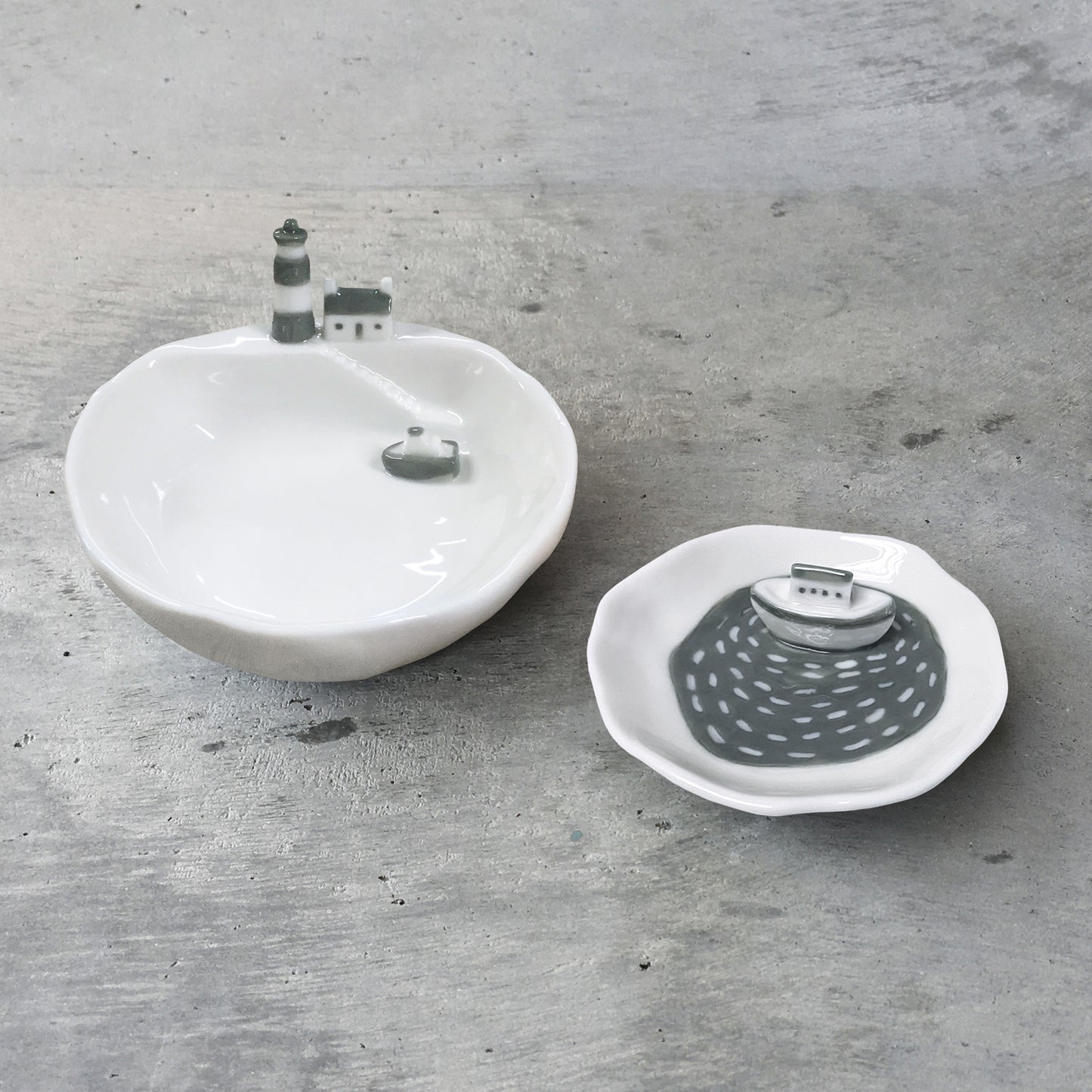 Two ceramic dishes, on with a lighthouse and the other with a boat