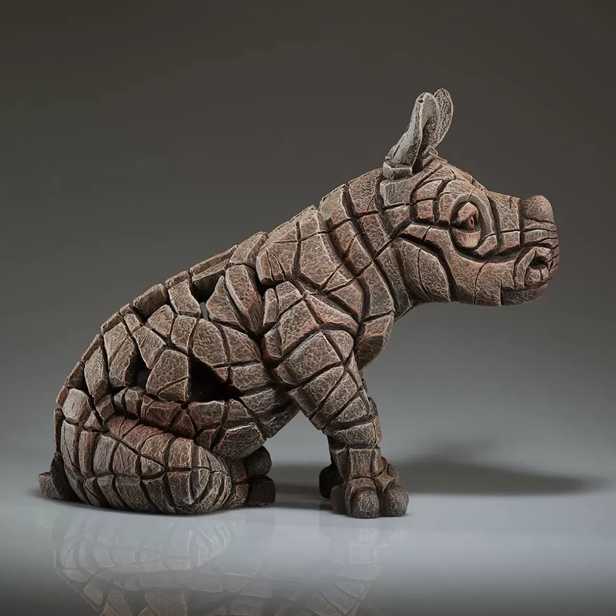 A textured and painted sitting rhino calf figure sculpture side view