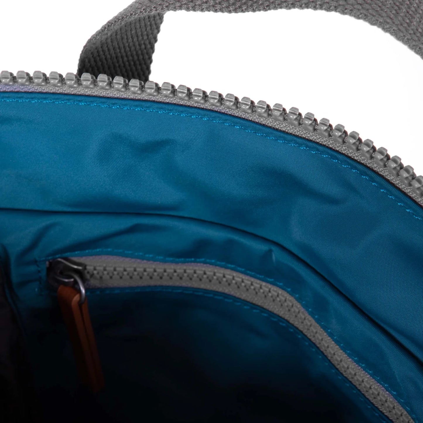 A nylon backpack in a marine blue colour with grey handles and interior zip pocket