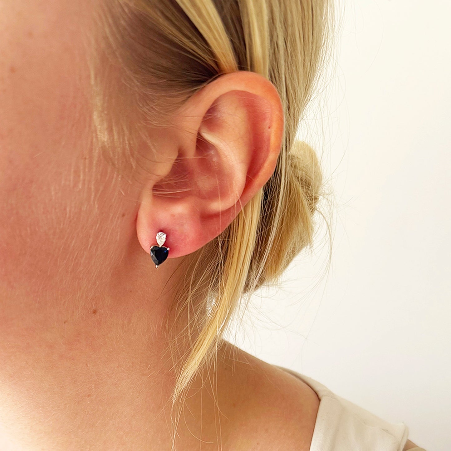 Model wearing silver sapphire CZ stud earrings with upside-down clear teardrop stone bail