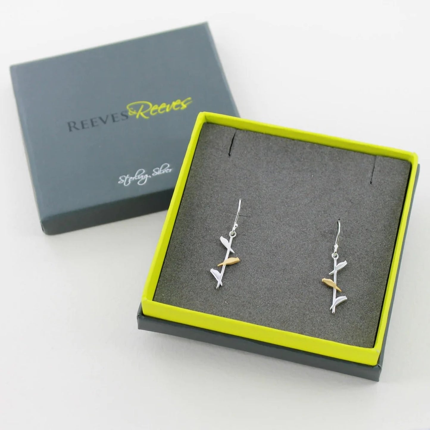 A pair of long drop earrings featuring three birds, the centre on in gold in branded box