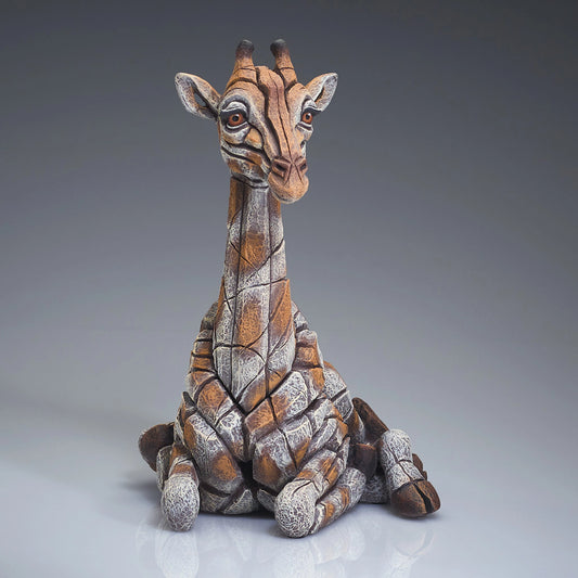 Front view of a modern sculpture of a sitting giraffe calf
