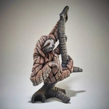 A textured and painted sloth on a branch figure sculpture back view