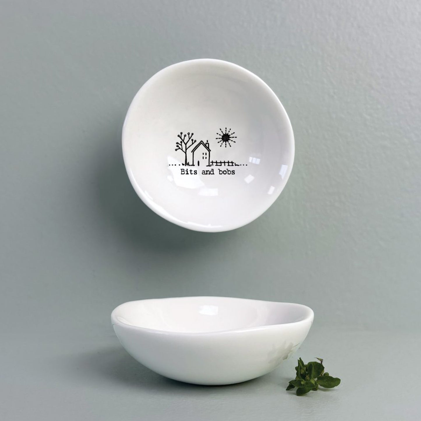 A white ceramic bowl featuring a house illustration and a quote