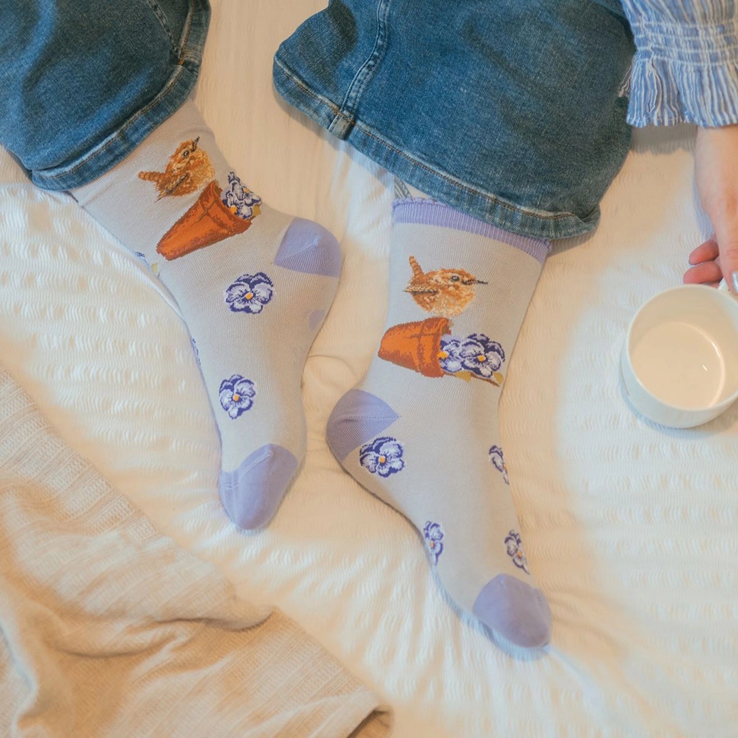 Model wearing grey bamboo socks with wren and pansy design