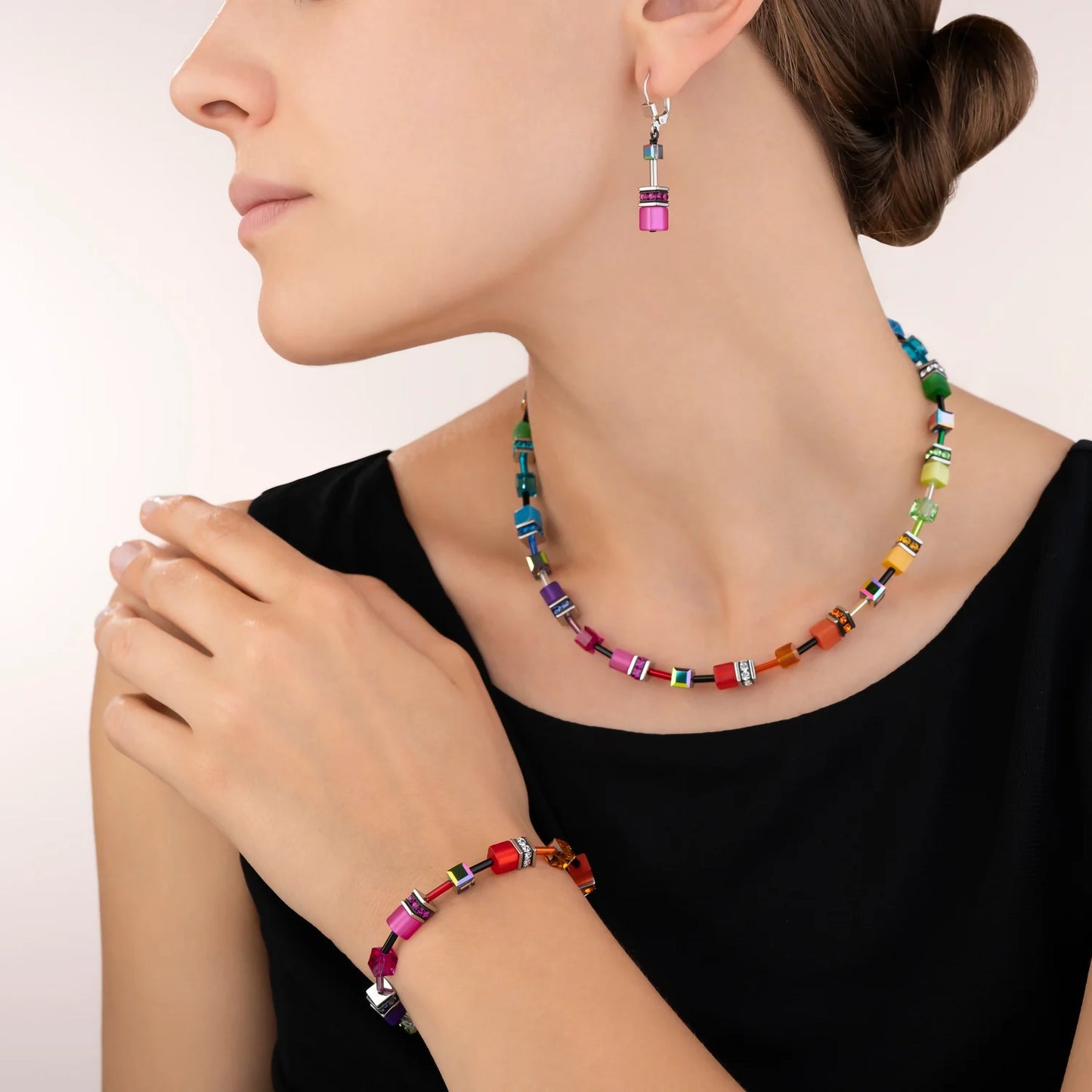Model wearing a set of rainbow coloured jewellery with a variety of cube shaped stones