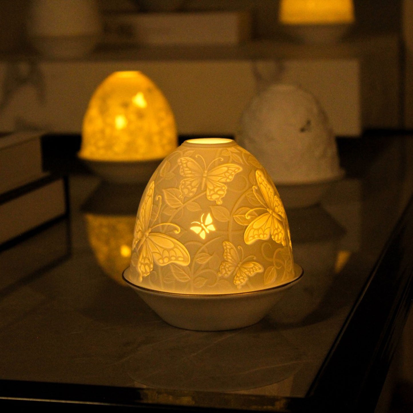 White porcelain tall dome candle holder with engraved butterflies and gold rimmed plate lifestyle