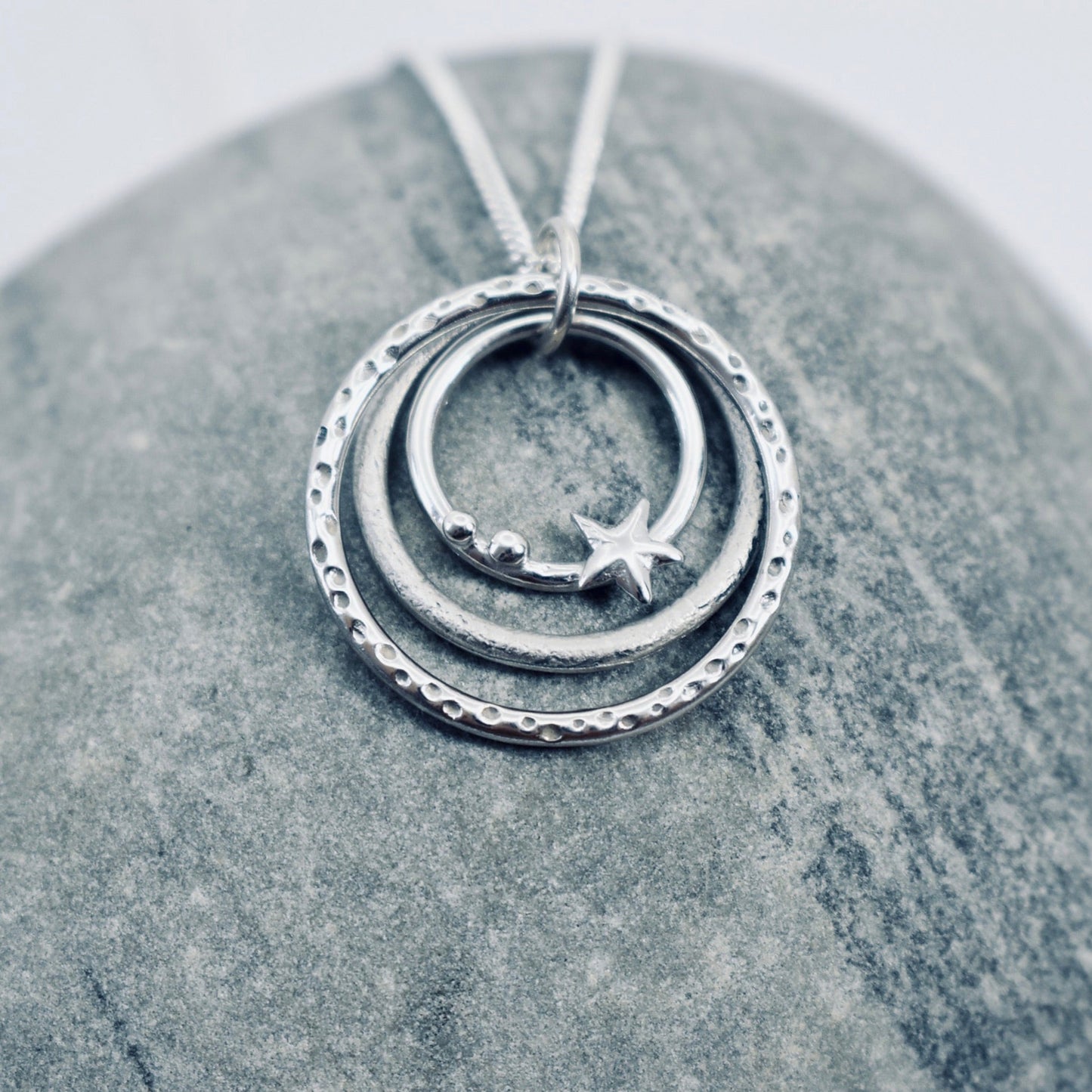 Silver necklace with three graduated circles with texture and pebble and star shapes