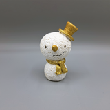 A snowman ornament with gold glitter details wearing a top hat and scarf