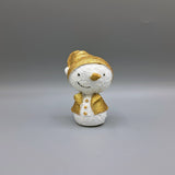 A snowman ornament with gold glitter details wearing a Santa hat and coat