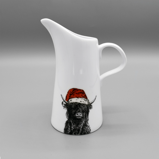 A white jug featuring a printed image of a Highland cow wearing a red Santa hat