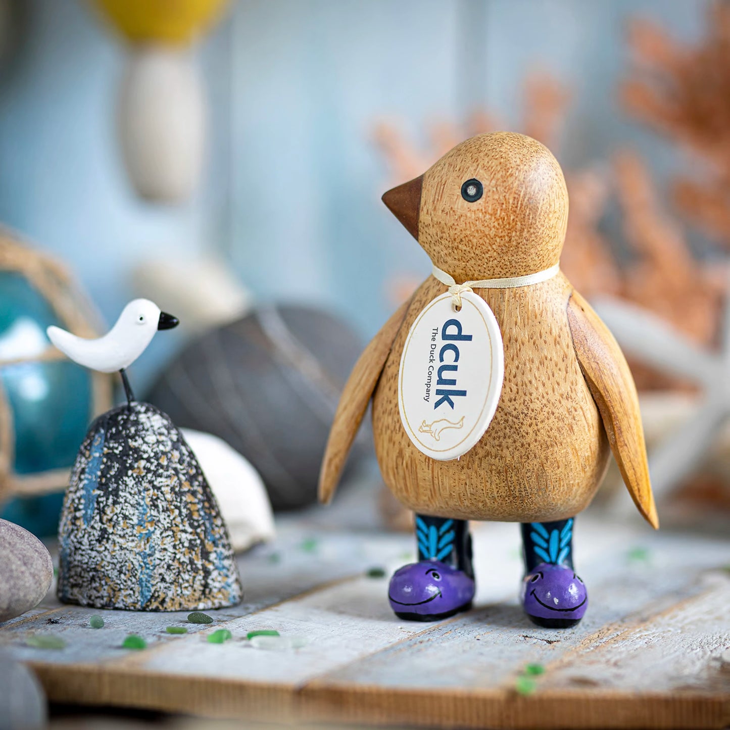 A wooden penguin wearing wellies with purple whale design lifestyle