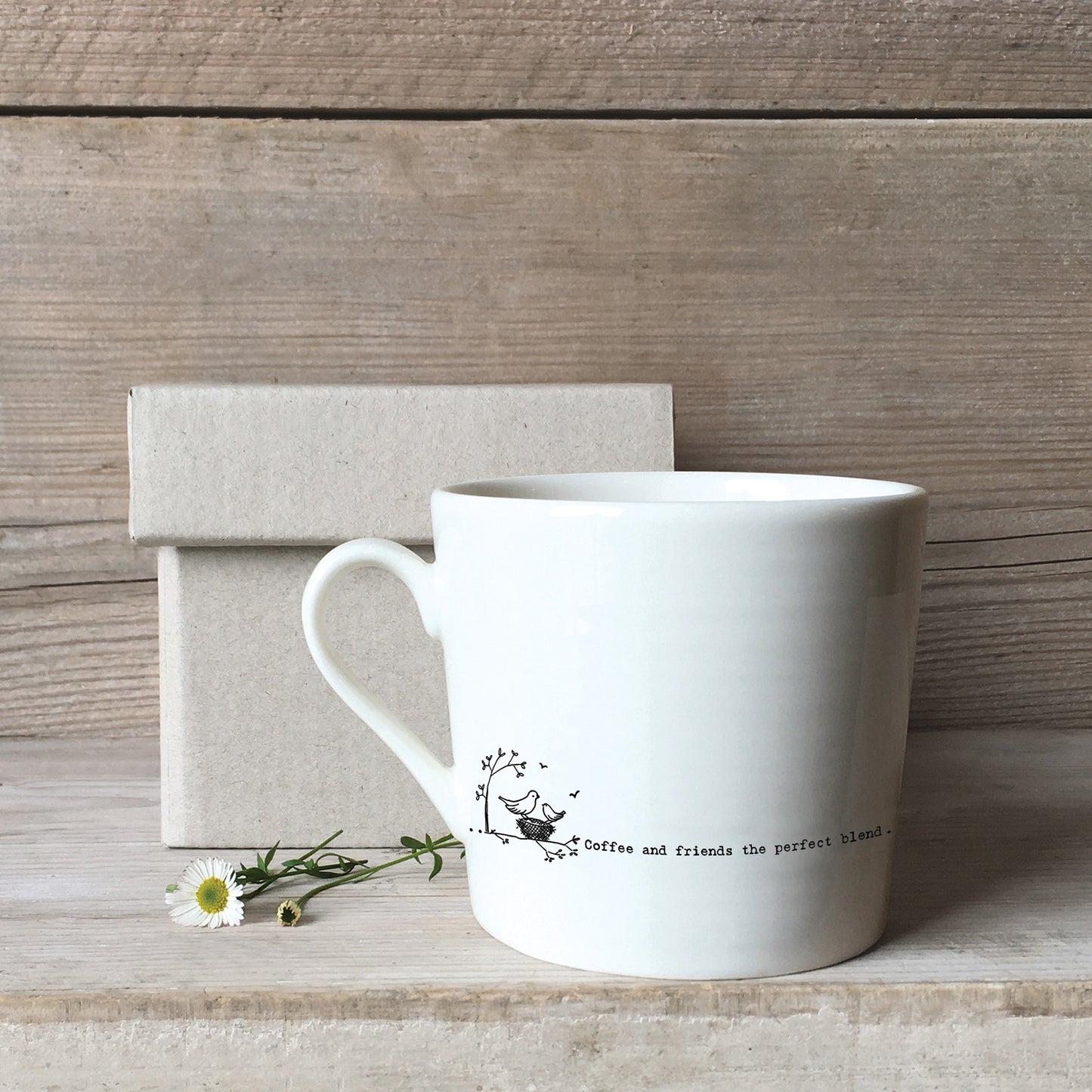 A white ceramic mug with a birds & nest illustration and a quote with a box