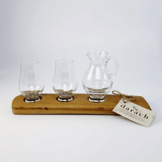 Single glass jug and two nosing whisky glasses on wooden barrel stave