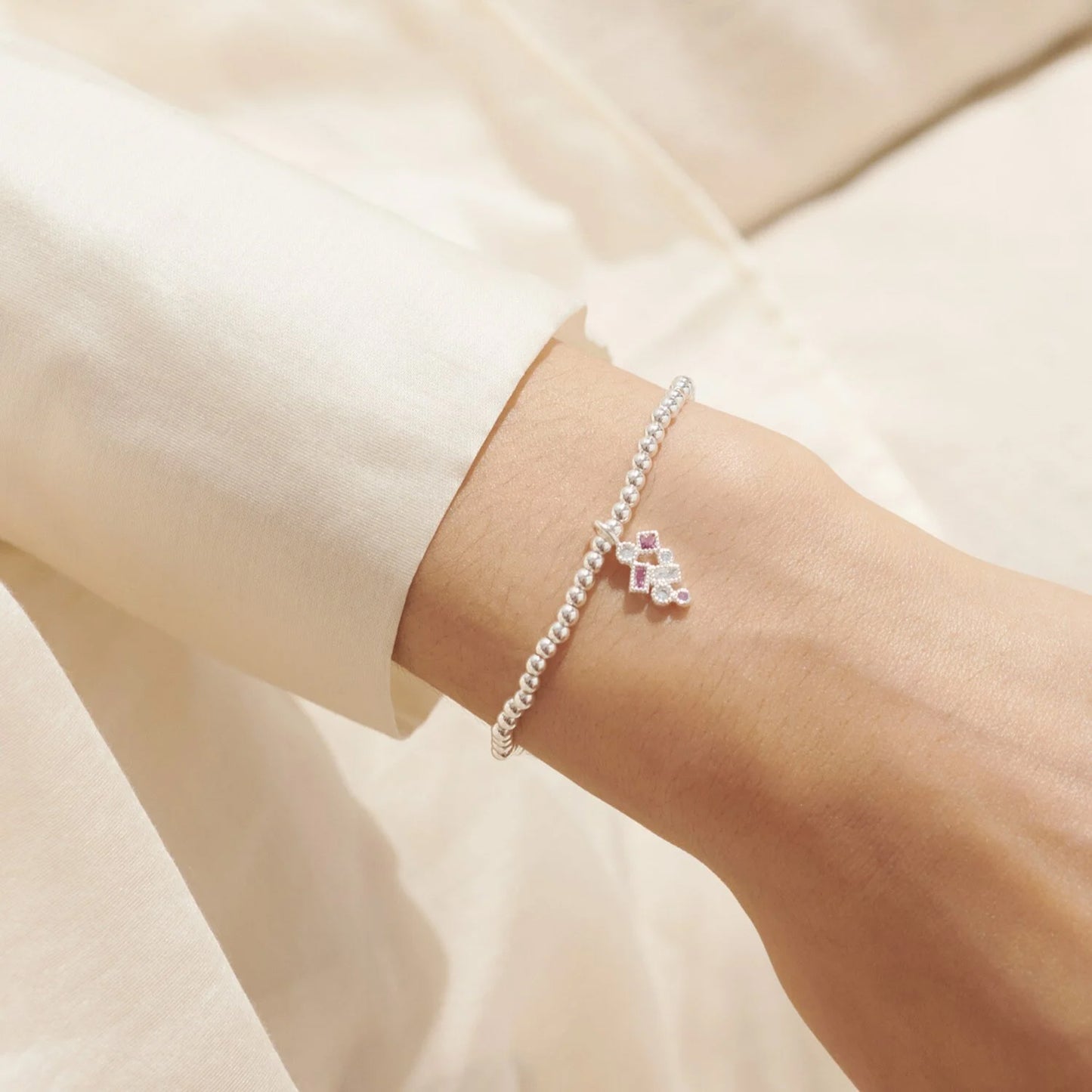 Silver bracelet with CZ constellation charm in pink and white on model