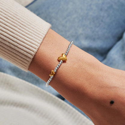 Model wearing silver beaded birth month bracelet for April with gold heart and butterfly charms