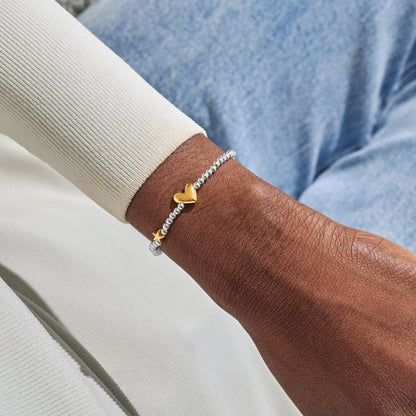 Model wearing silver beaded bracelet with a gold heart and star charm