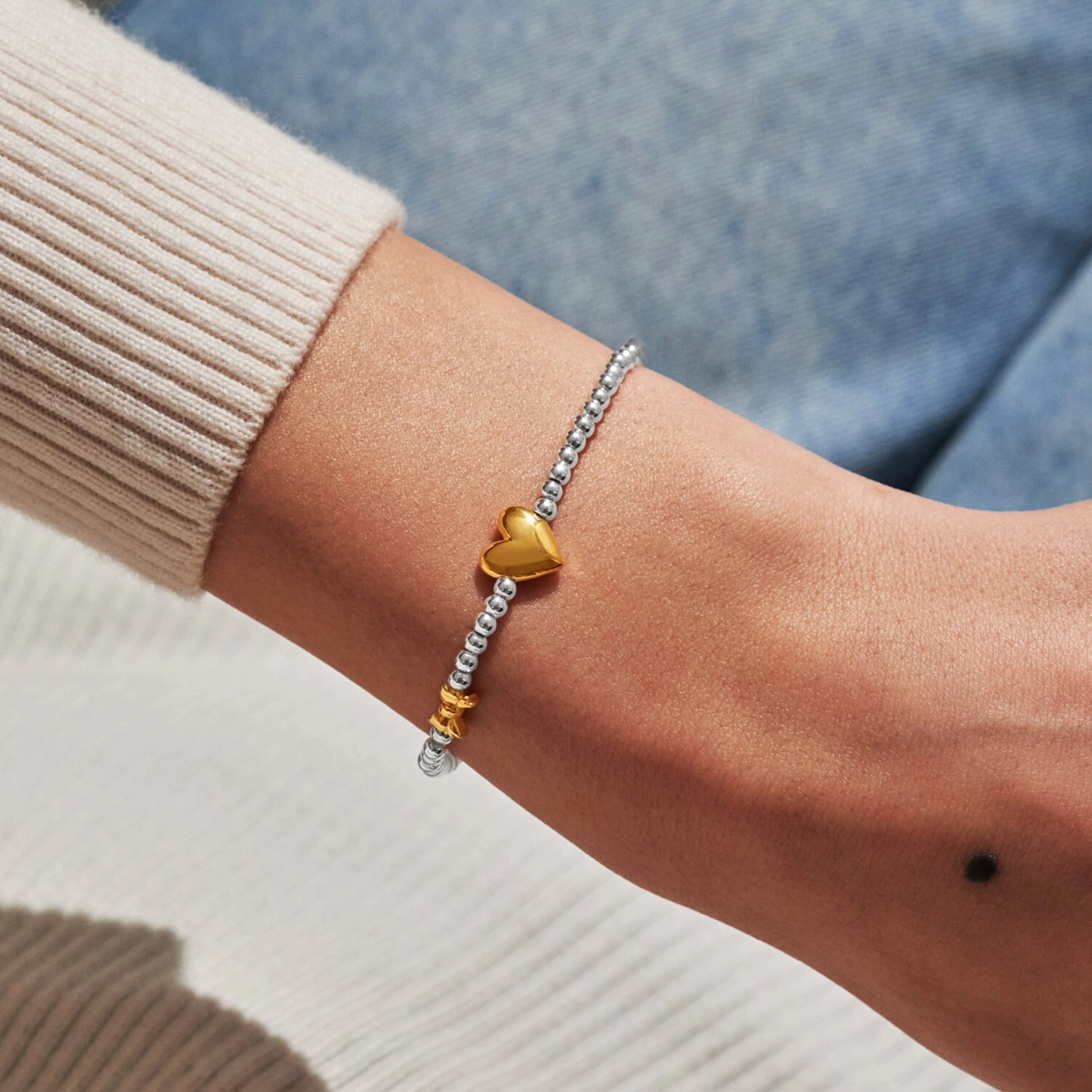 Model wearing silver beaded birth month bracelet for January with gold heart and bow charms