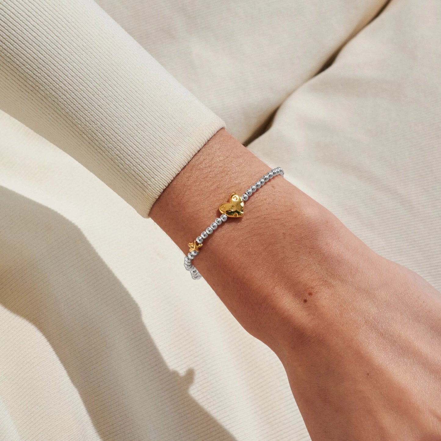 Model wearing silver beaded birth month bracelet for July with gold heart and starfish charms