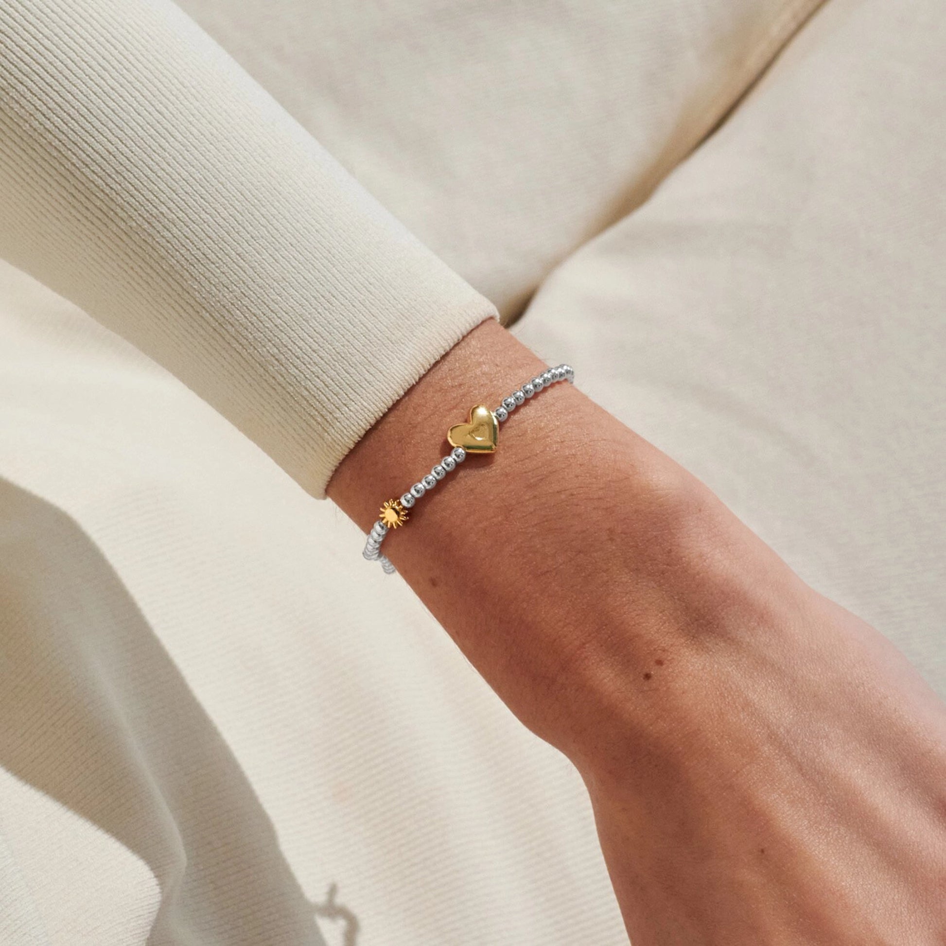 Model wearing silver beaded birth month bracelet for June with gold heart and sun charms