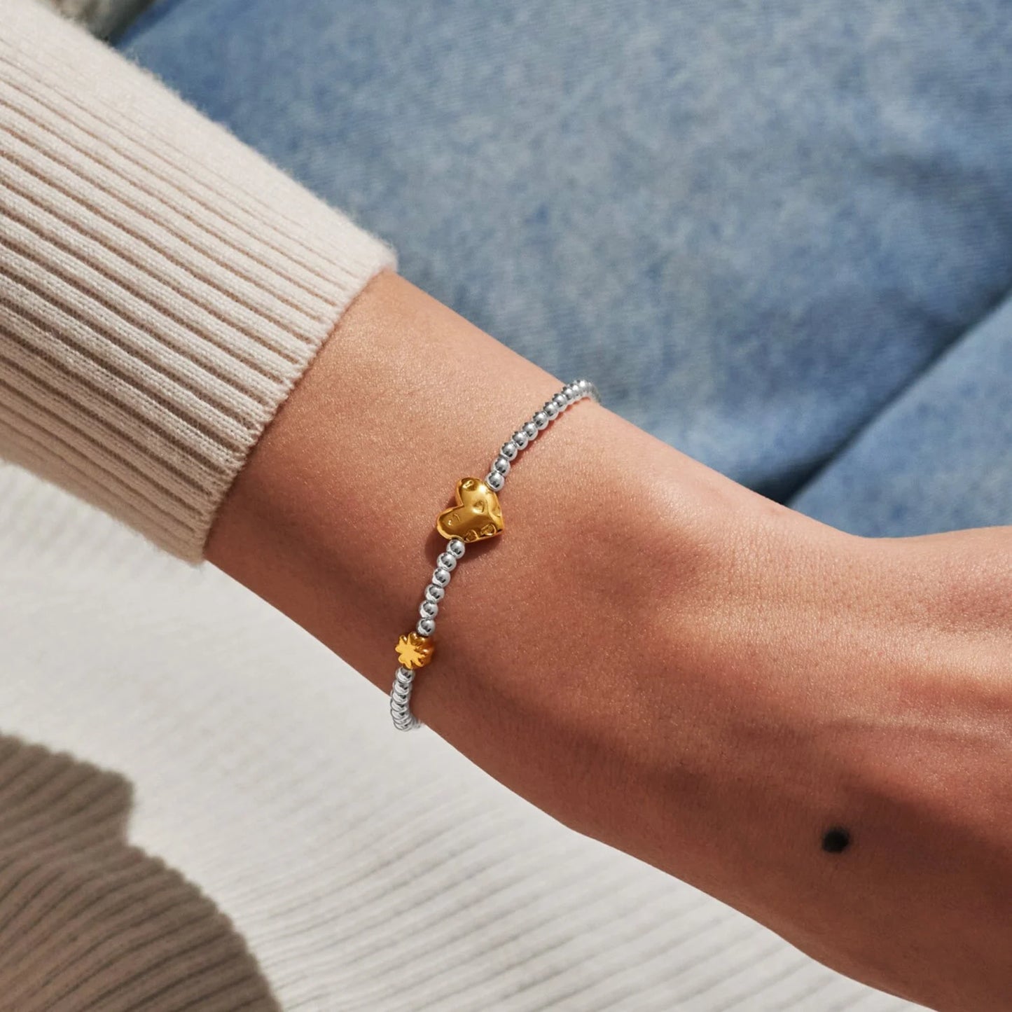 Model wearing silver beaded birth month bracelet for March with gold heart and clover charms