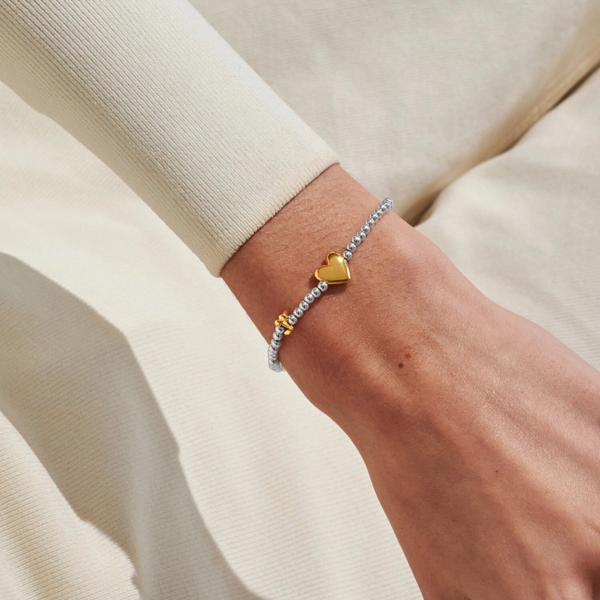 Model wearing silver beaded birth month bracelet for May with gold heart and cherry charms 