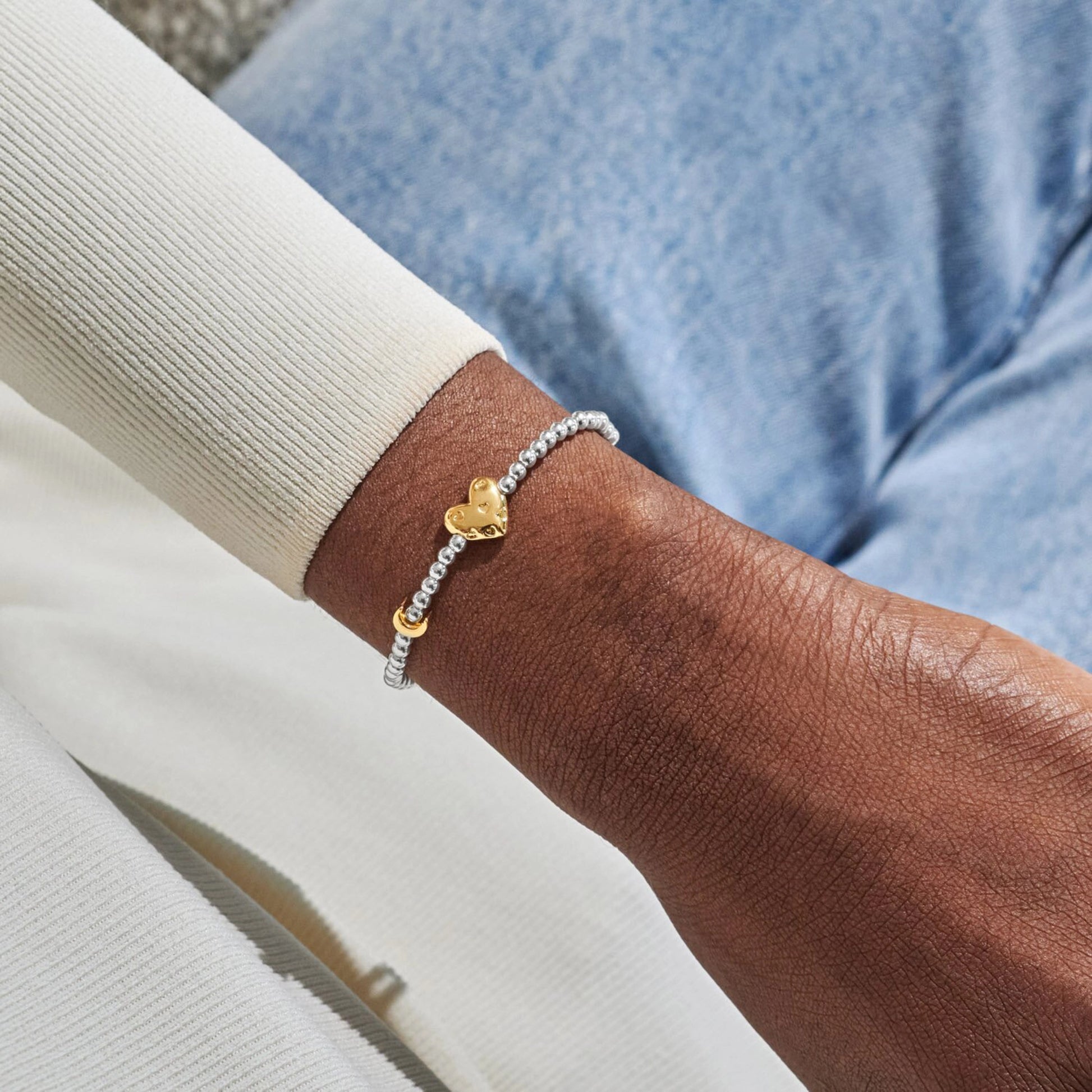 Model wearing silver beaded birth month bracelet for October with gold heart and padlock charms