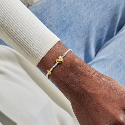 Model wearing silver beaded birth month bracelet for October with gold heart and padlock charms 