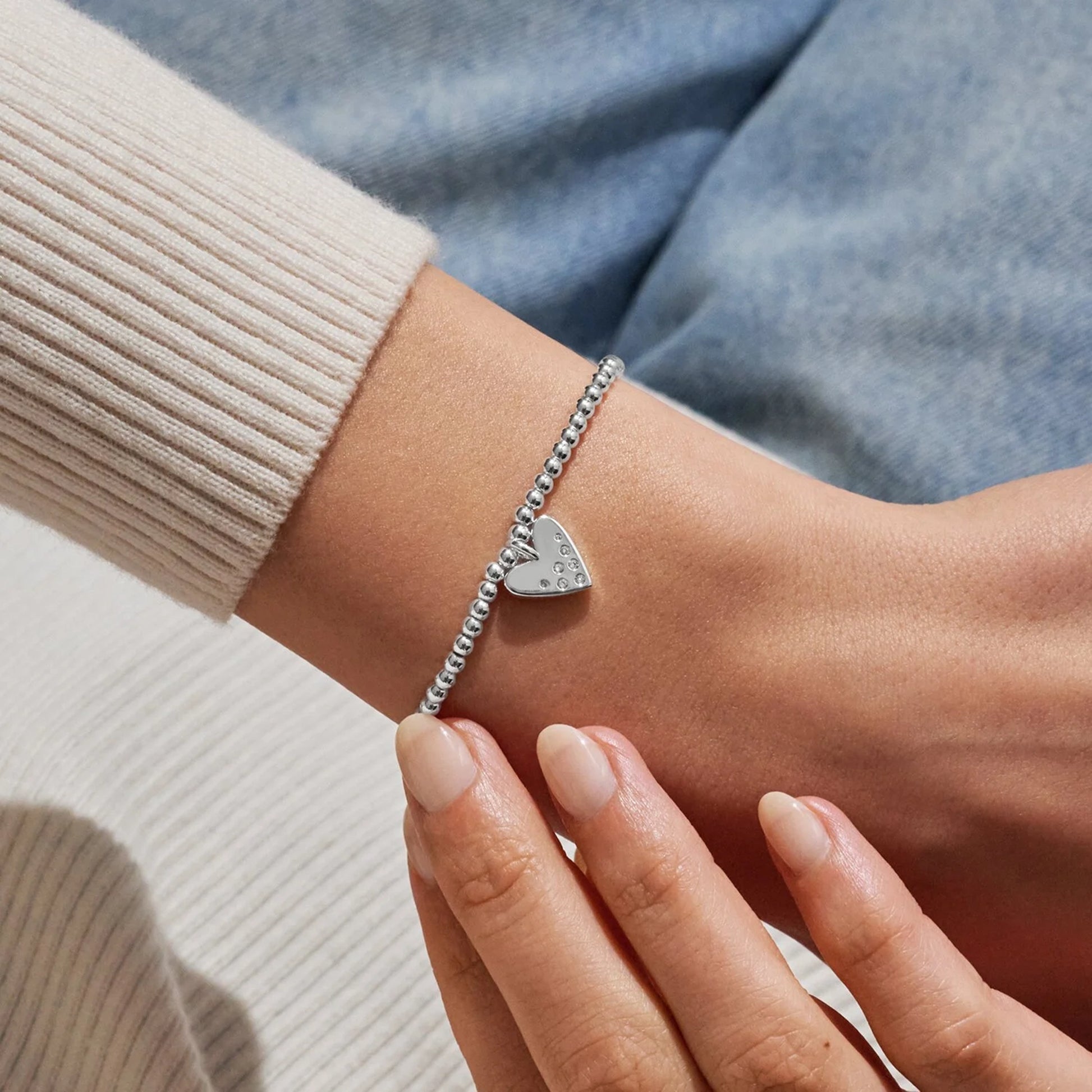 Model wearing silver beaded bracelet with heart charm set with a constellation of CZ stones