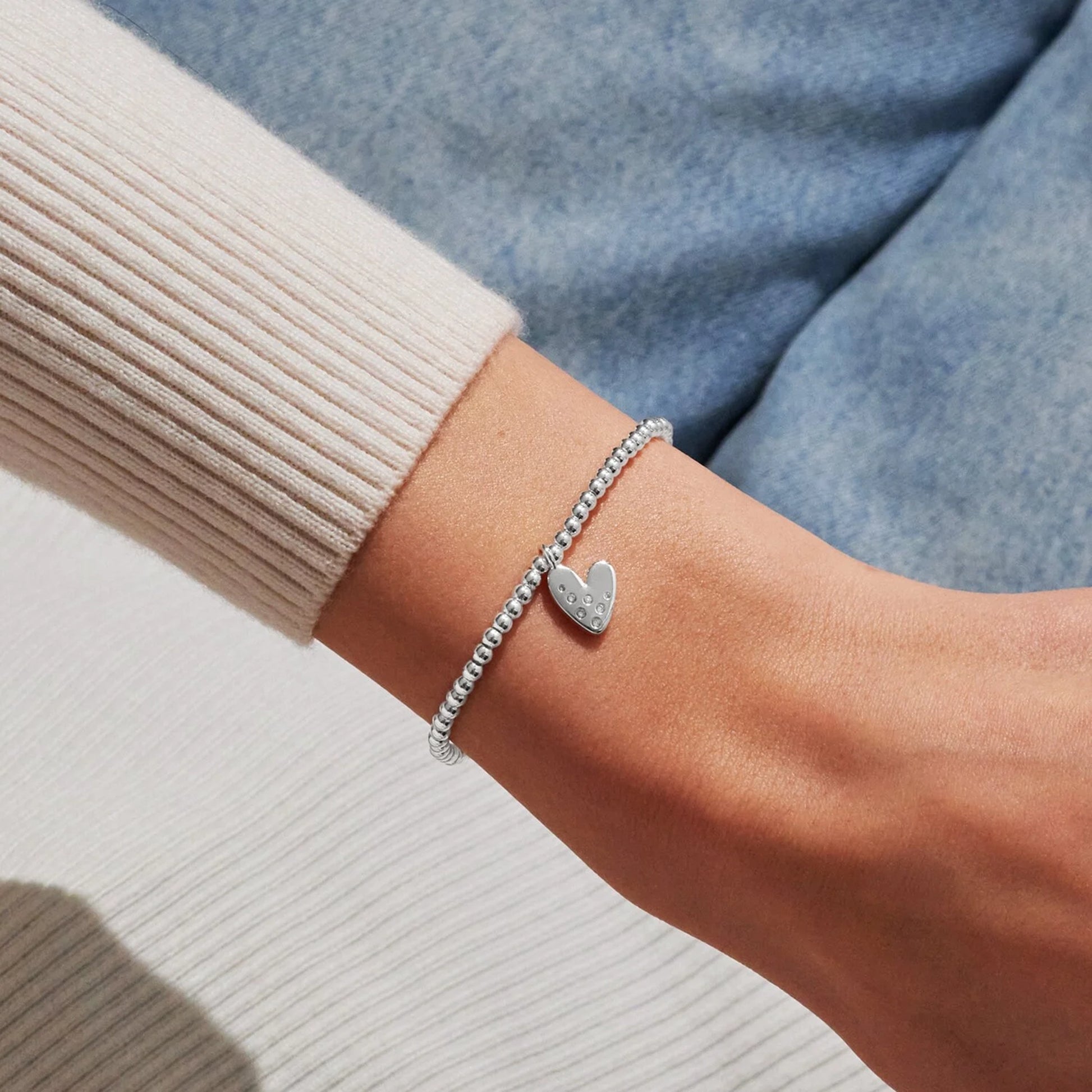 Model wearing silver stretch beaded bracelet with a heart charm set with a constellation of CZ stones