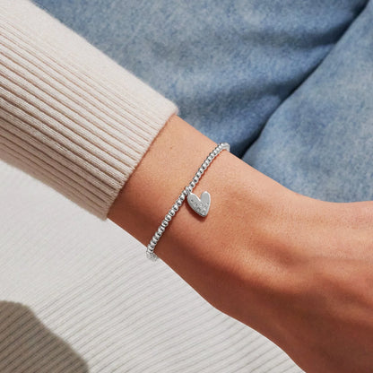 Model wearing silver stretch beaded bracelet with a heart charm set with a constellation of CZ stones