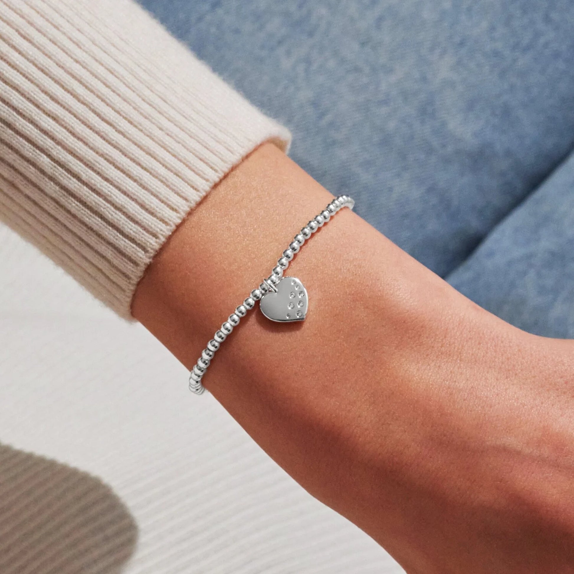 Model wearing silver stretch bracelet with heart shaped charm set with CZ stones