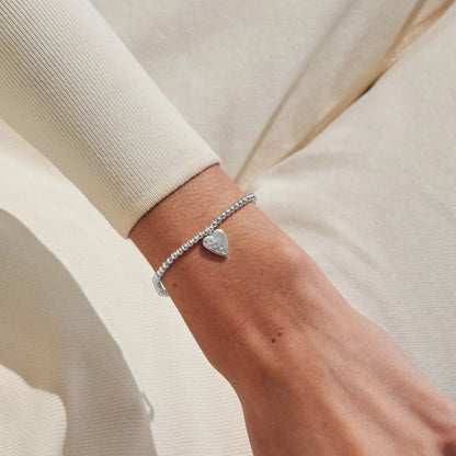 Model wearing silver stretch bracelet with heart charm set with a constellation of CZ stones
