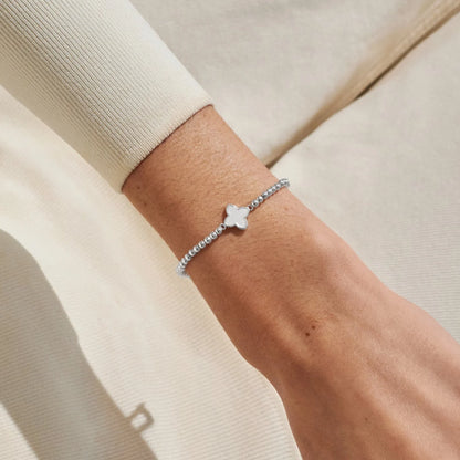Model wearing silver beaded bracelet with clover and mother of pearl charm