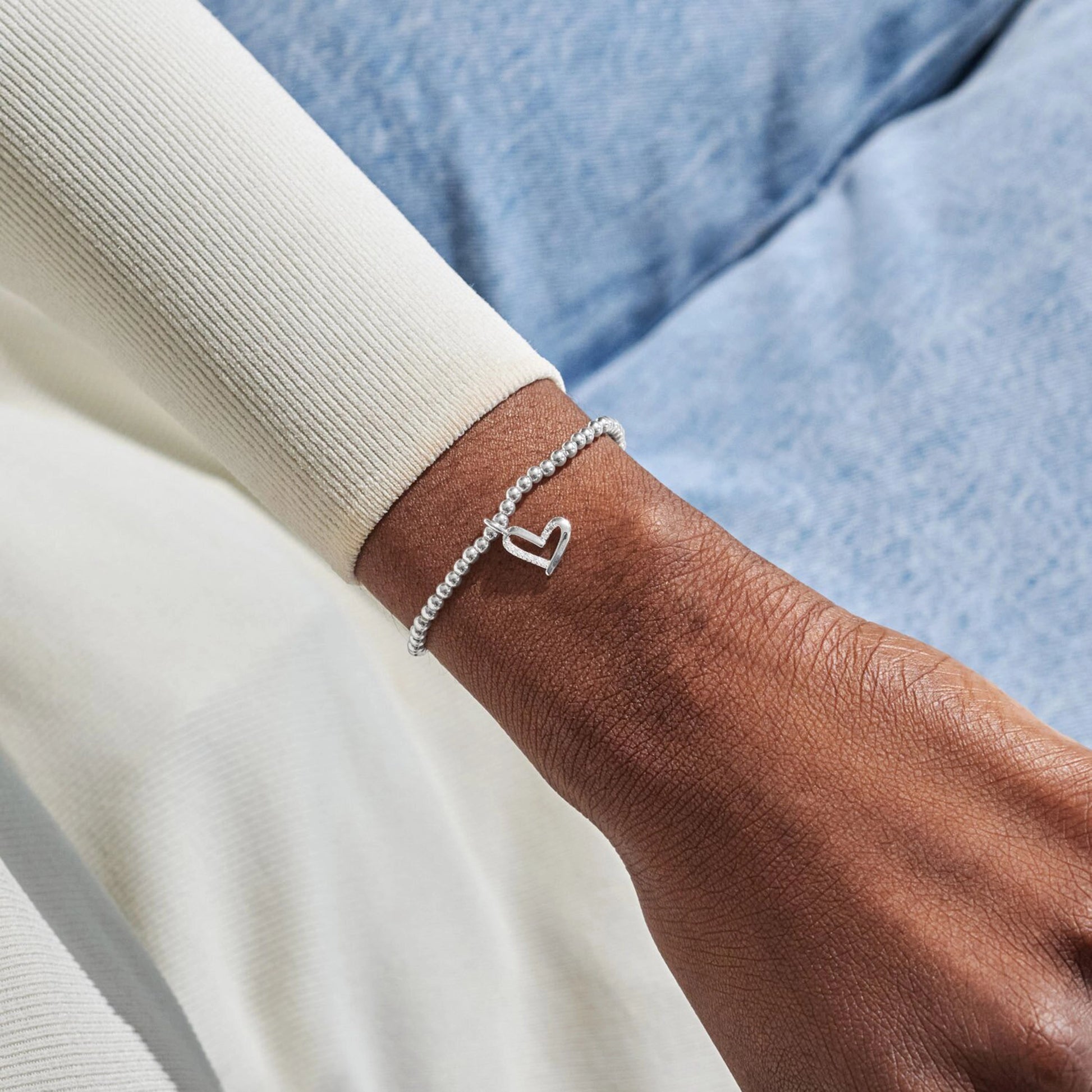 Model wearing silver beaded bracelet with CZ set open heart charm
