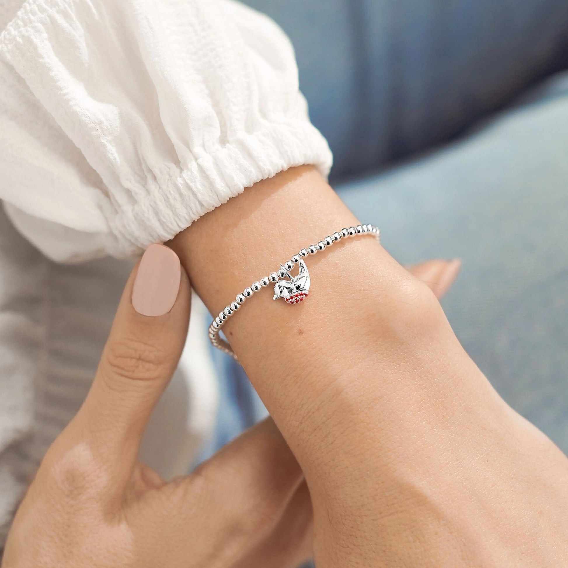 Model wearing silver beaded bracelet with little robin charm set with red CZ stones