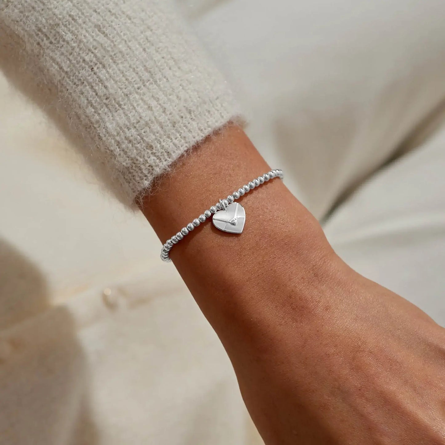 Silver beaded bracelet with heart shaped envelope charm on model