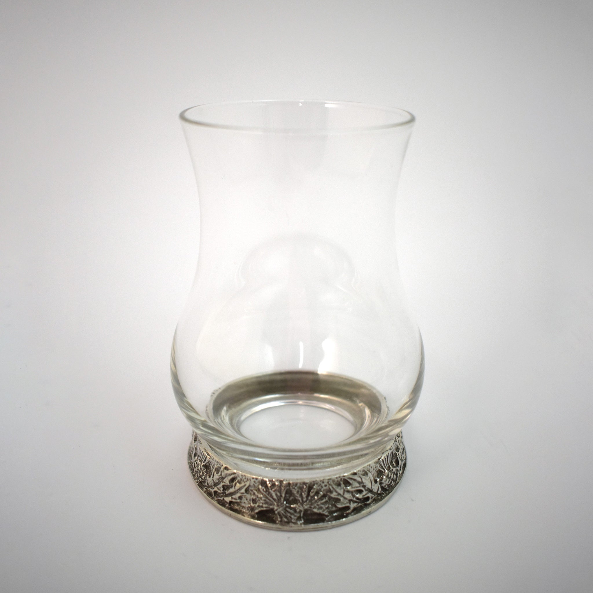 A whisky glass with a pewter base engraved with thistles