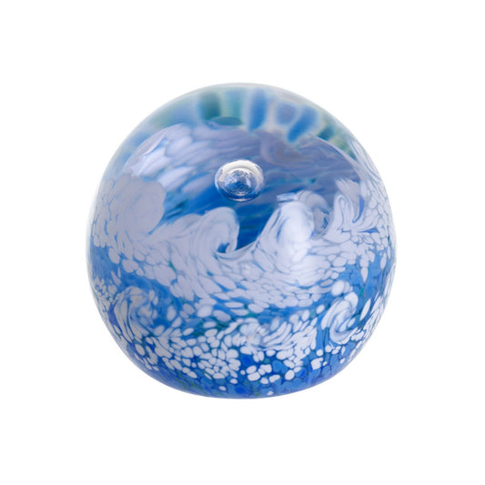 A glass paperweight with blues and white foaming ocean wave shapes