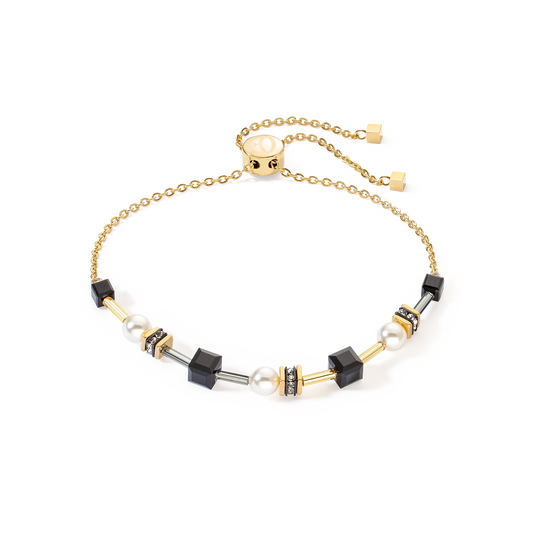A gold chain bolo bracelet with black cube beads and white pearls