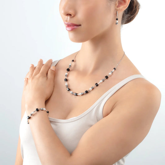 Model wearing steel chain bolo necklace and bracelet with black cube beads and white pearls