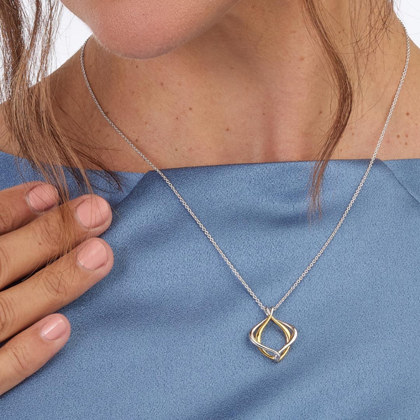 Model wearing a double silver and gold paseo shaped pendant with silver chain
