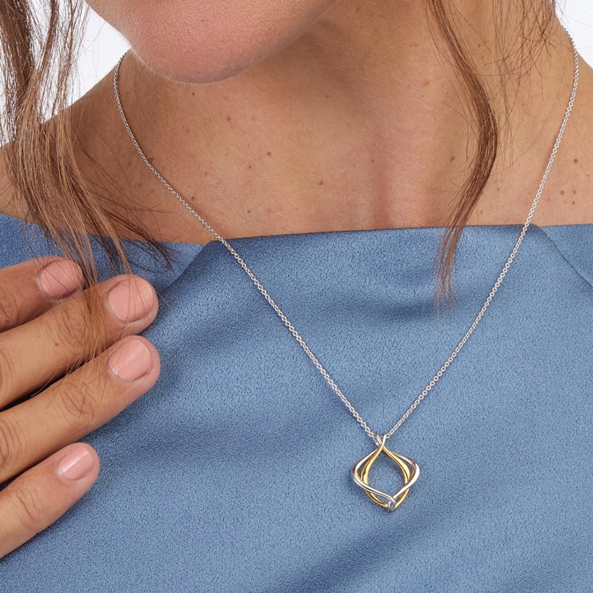 Model wearing a double silver and gold paseo shaped pendant with silver chain