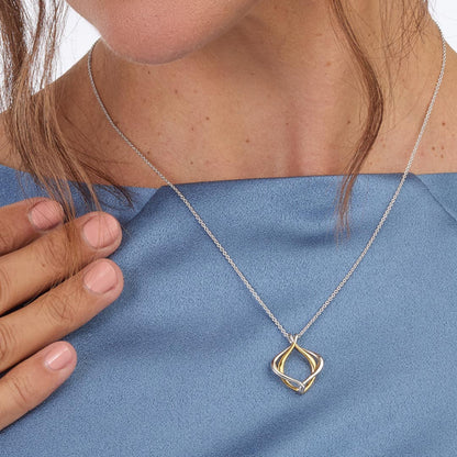 Model wearing a double silver and gold paseo shaped pendant with silver chain