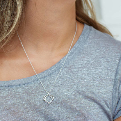 Model wearing a double silver paseo shaped pendant with silver chain