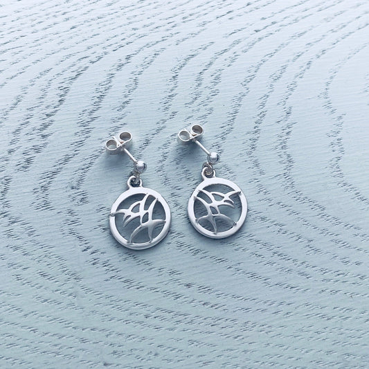 A pair of silver drop earrings with flying birds in round frames and stud post fittings