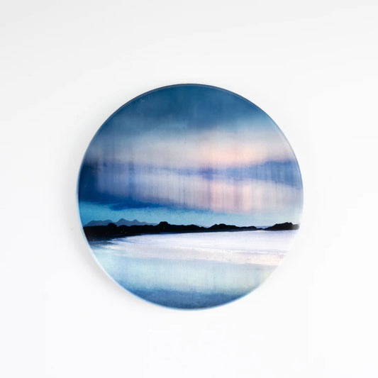 A round coaster featuring an Aurora artwork by Cath Waters in blues and purples